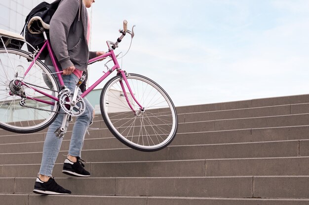 인식할 수 없는 젊은 남자가 자전거를 들고 생태학적 라이프스타일의 계단 개념