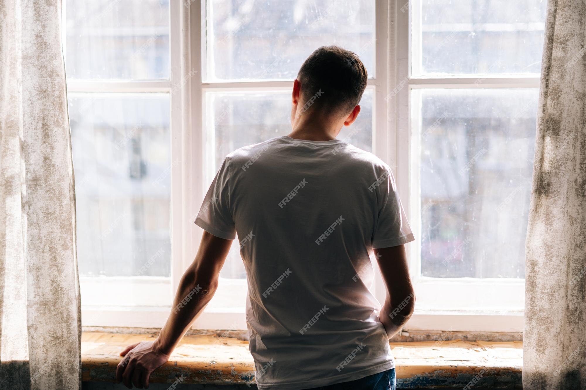 Premium Photo  Unrecognizable young man stands by the window