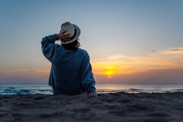 ビーチで夕日を楽しんでいる認識できない若い女性