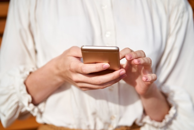 Unrecognizable young woman is holding smartphone and typing