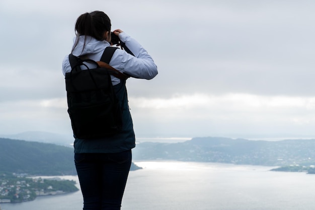 写真 彼のバックパックと彼のカメラとノルウェーのベルゲンの街と写真の若い女性を認識できません。