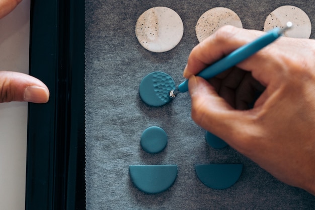 Photo unrecognized artisan making colorful earrings with clay and making a design.