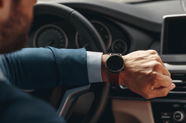 Unrecognized male is checking the time during the driving a car