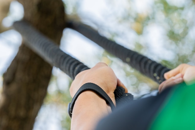 Unrecognized person working out in the park and using a rope climb.