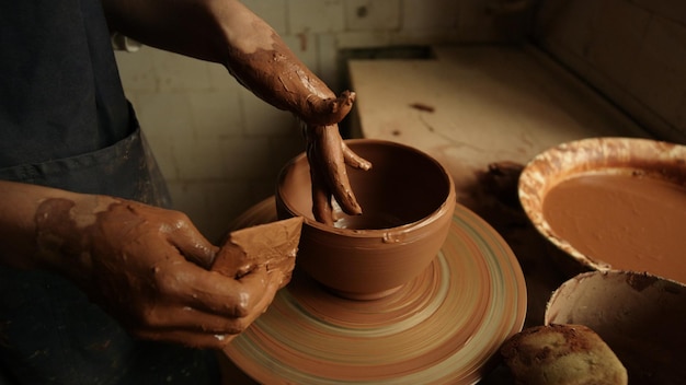 Unrecognized woman sculpting clay pot in workshop Closeup lady making product on potters wheel in studio Unknown girl working with wet clay in pottery