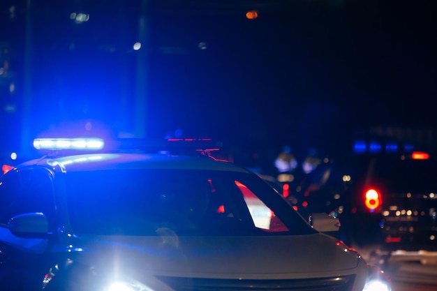 Foto auto della polizia stradale irriconoscibile con la luce della sirena rossa e blu accesa sul tetto sulla strada della città di notte