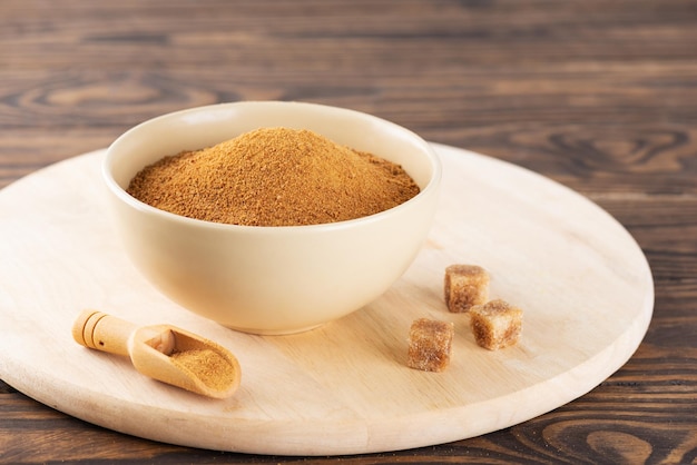 Unrefined cane sugar Panela in a bowl on a wooden board