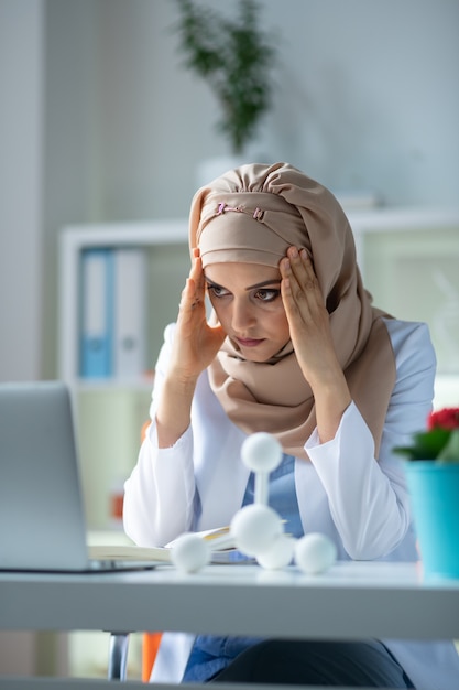 Unsatisfied after experiment. Female chemist wearing headscarf feeling unsatisfied after experiment