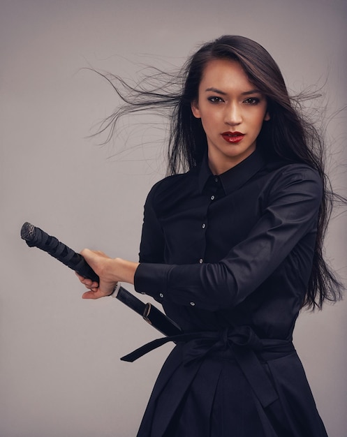 Unsheathing her blade Studio portrait of a beautiful young woman in a martial arts outfit wielding a samurai sword