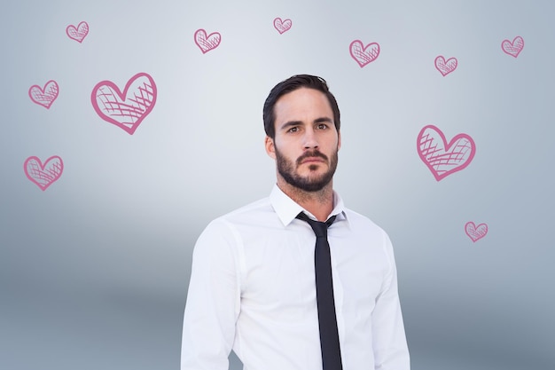 Unsmiling businessman standing with hands in pockets against grey vignette