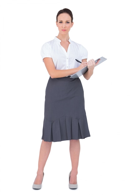 Unsmiling businesswoman holding clipboard