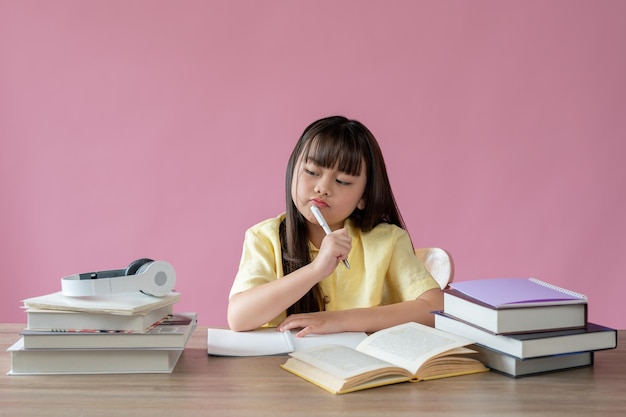 An unsure and thoughtful young Asian girl doing homework at her study table