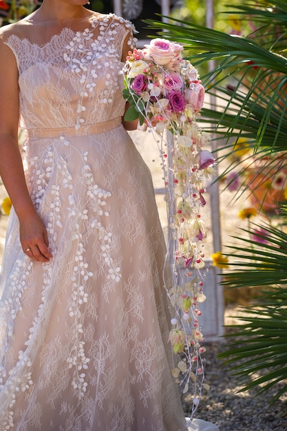 An unusual elongated wedding bouquet in the hands of the bride