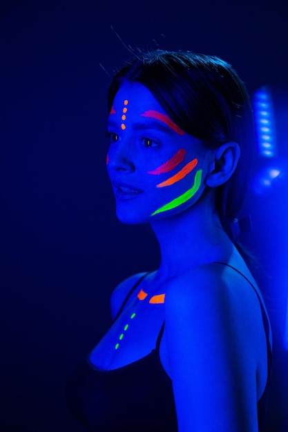 Unusual fluorescent makeup on the skin of a beautiful woman glowing under ultraviolet light