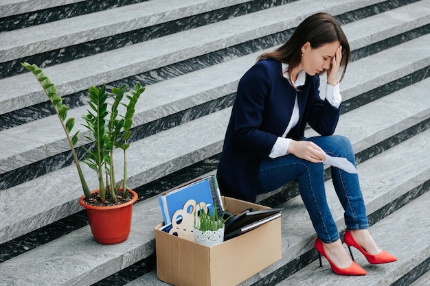 Photo unveiling vulnerability depressed middleaged woman reading the letter sitting on stair employment crisis unveiled depressed female worker in crisis