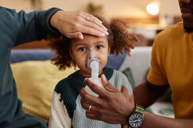 Photo unwell little girl with parents inhaling medicine