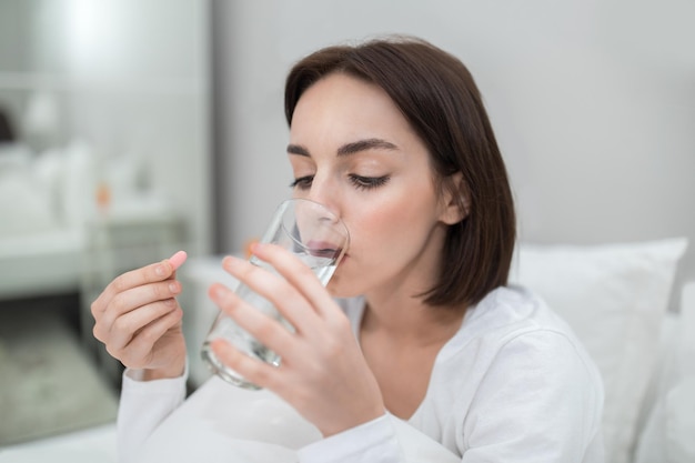 Unwell young lady taking painkiller at home