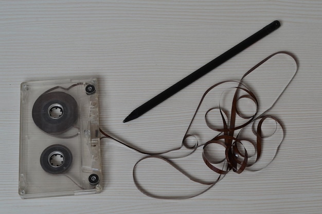 An unwound cassette tape and a pencil lie on a light table