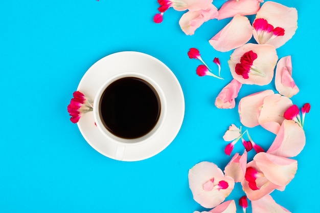 Su un caffè e petali di rosa su un tavolo blu. buongiorno concetto