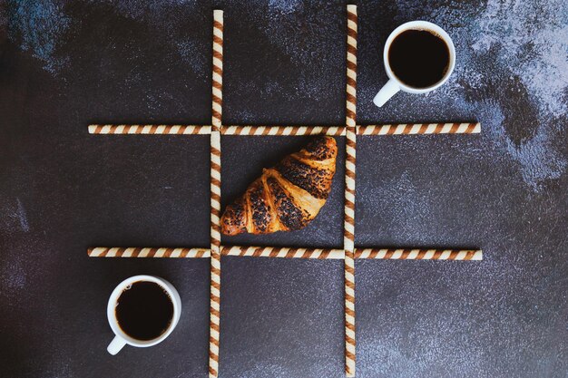 up of hot coffee and croissant on black background. Top view, copy space, mockup. Flat lay. Healthy