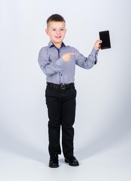 写真 育成と開発 小さな男の子 正装 携帯電話 かわいい男の子がスマートフォンを握る モバイル テクノロジー アプリケーションをダウンロード モバイル通信 現代のガジェット 中小企業