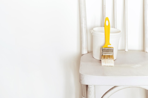 Upcycling concept. Repainting an retro chair. Old white wooden chair against white wall.