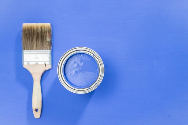 Upened metal paint can with purple paint and paint brush.