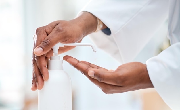 Upholding protocol to prevent the spread of germs Closeup shot of an unrecognisable doctor using hand sanitiser in a clinic