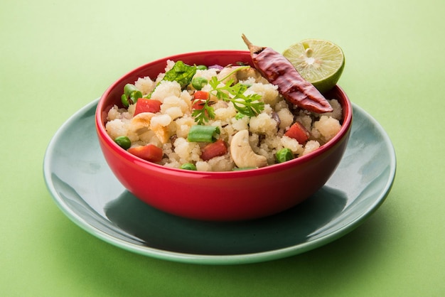 Photo upma or uppittu is a popular breakfast dish in south india and maharashtra. semolina or rava or coarse rice flour is main ingredients. served in a bowl over colourful or wooden background