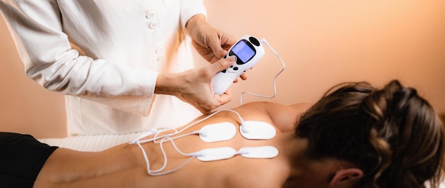 Photo upper back physical therapy with tens electrode pads transcutaneous electrical nerve stimulation