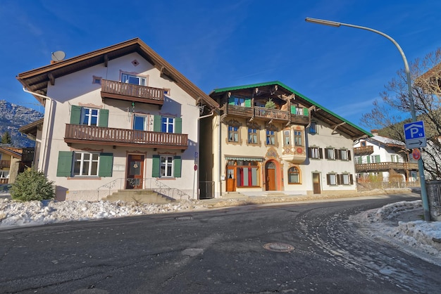 Garmisch-Partenkirchen에 있는 상부 바이에른 스타일의 주택으로 밝은 색상으로 칠해진 창 셔터와 사랑스럽게 칠해진 정면이 있습니다. 독일 남부 바이에른