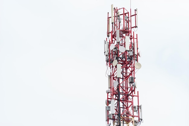 Upper part of the radio tower with installed antennas and other equipment against a white cloudy sky