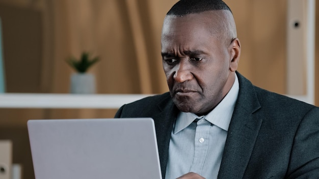 Upset African American businessman elderly man looking in laptop