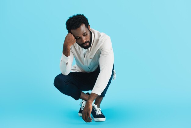 Upset african american man sitting isolated on blue