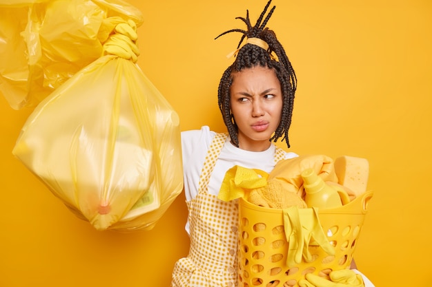 Upset Afro American woman looks with aversion at trash bag