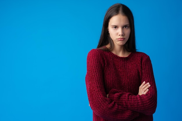 写真 青の背景に隔離されたカメラを見て動揺して気分を害した10代の少女