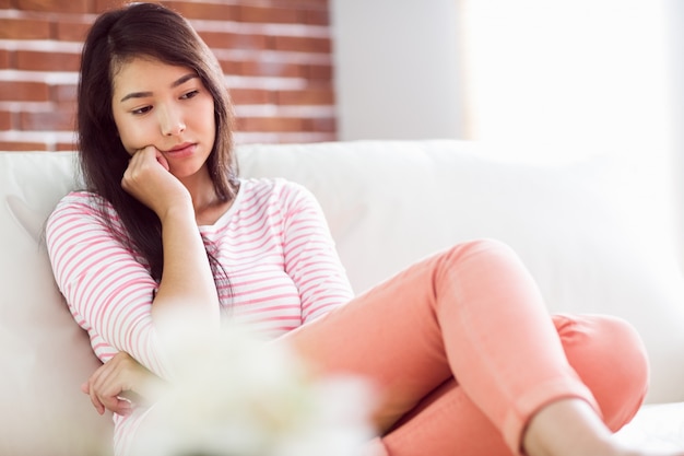 upset asian woman on couch 