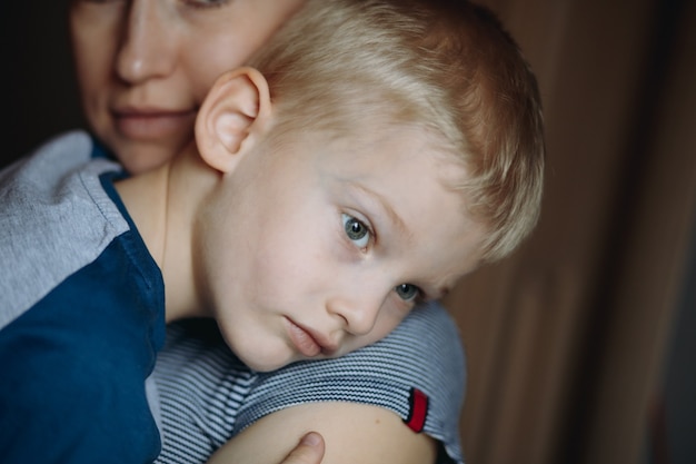 upset boy lay on his mother shoulder Mon hugging son