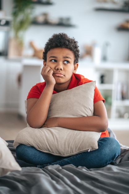 Upset. A boy with a pillow in hands looking upset