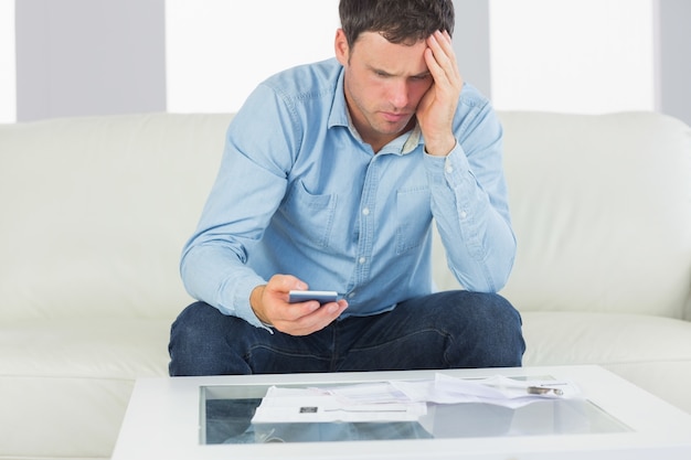 Upset casual man using calculator paying bills