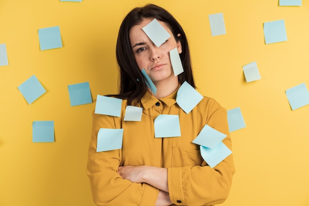Upset, charming girl with stickers on her face isolated on yellow wall