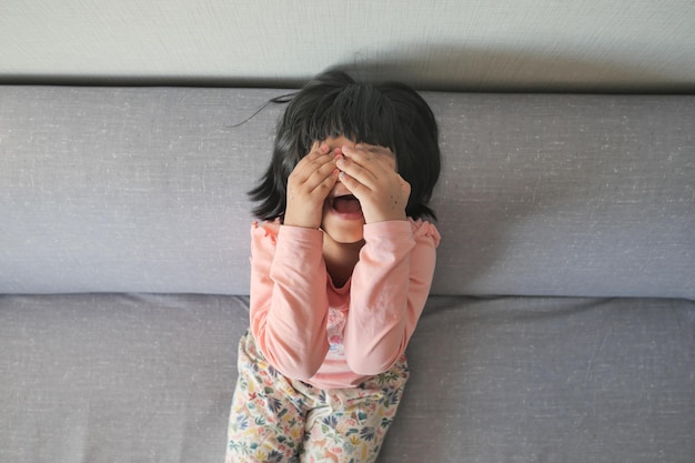 A upset child girl cover her face with hand