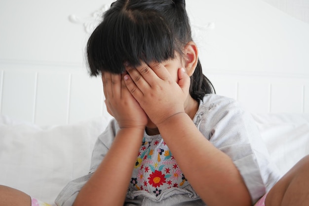 A upset child girl cover her face with hand