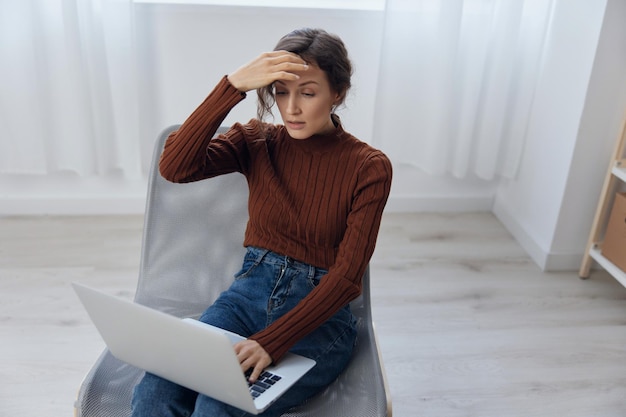 Upset confused irritated shocked curly adorable woman made\
critical mistake in document doing facepalm closing eyes touch\
forehead sitting in chair with laptop on knees at home office\
remote job