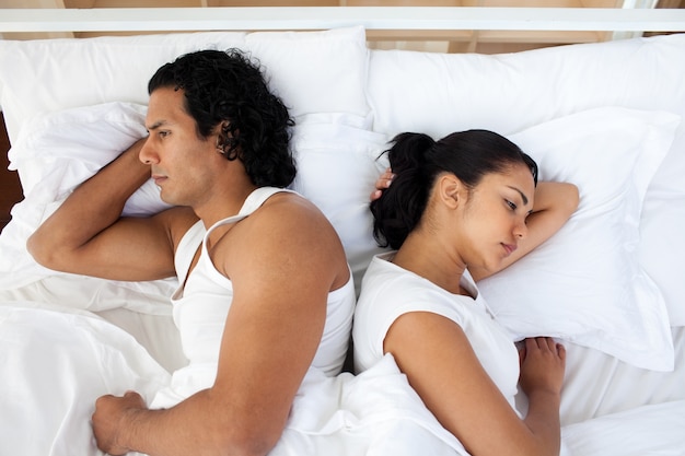 Upset couple in bed sleeping separately 