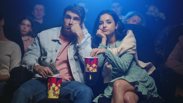 Фото Расстроенная пара ест попкорн в кинотеатре разочарованные люди смотрят фильм в зале