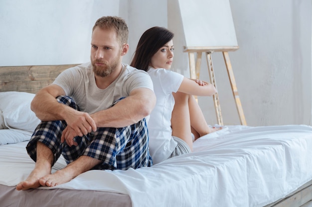 Upset couple sitting back to back after having an argument and trying to calm down