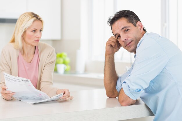 Upset couple with newspaper sitting in kitchen
