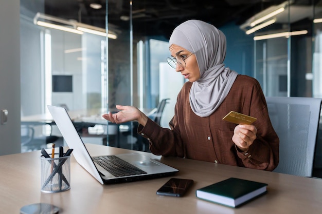 Upset and deceived business woman in hijab trying to transfer funds online lack of money in scammers