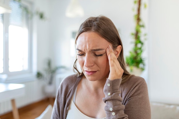 Donna depressa turbata che sente forte mal di testa emicrania triste stanca sonnolenta esausta donna che riposa